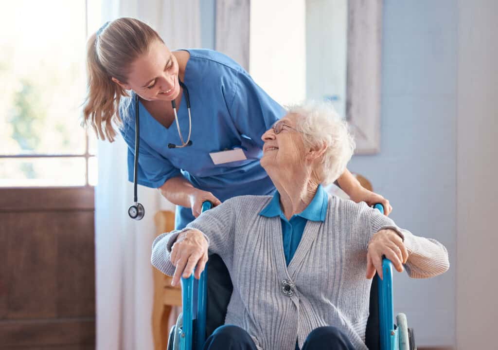 A nurse helping an elderly woman in a wheelchair.