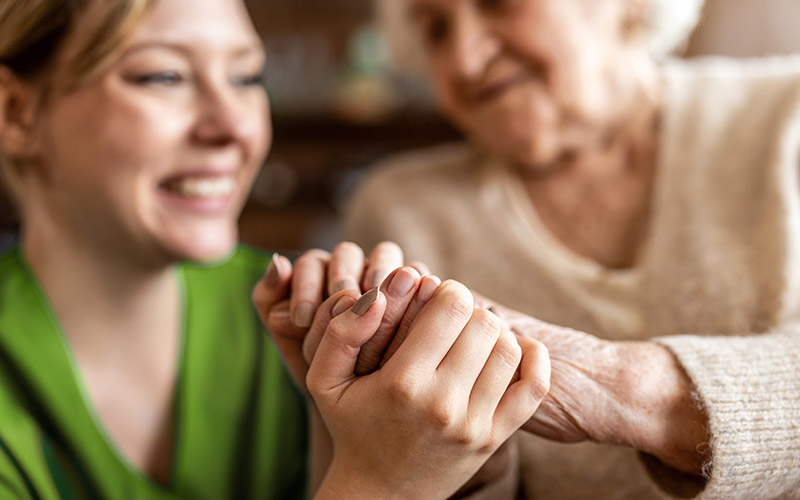 A woman holding the hand of an elderly woman.
